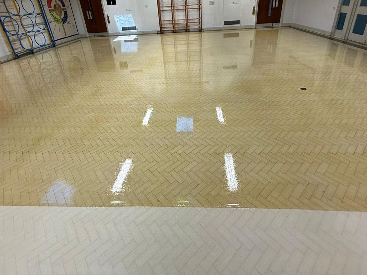 Herringbone Granwood block floor part-way through sealing, with a glossy sealed area beyond an unsealed strip